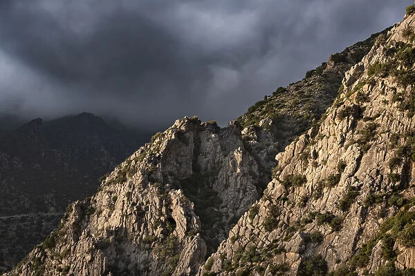 Sunset light on a rocky mountain and dark clouds in the sky, Chefchaouen, Morocco