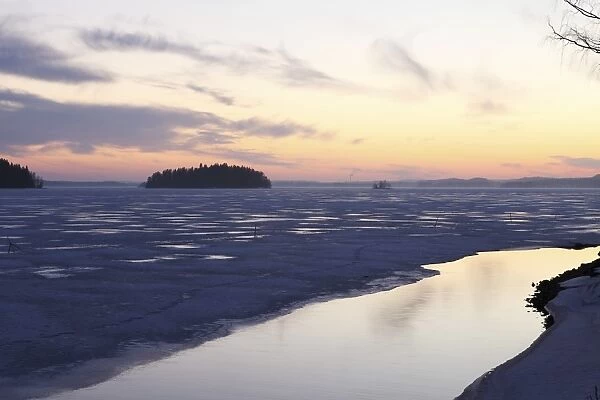 Sunset over the mainly frozen surface of Lake Pyhajarvi, the ice surrounds islands, at Tampere, Pirkanmaa, Finland, Scandinavia, Europe