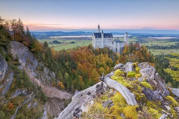 Sunset on Neuschwanstein Castle surrounded by colorful woods in autumn, Fussen, Bavaria