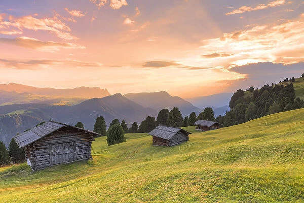 Sunset above traditional huts in the pasture. Gardena Valley, South Tyrol, Dolomites, Italy, Europe