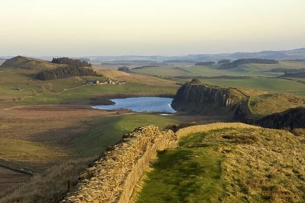 Towards sunset, view east along Hadrians Wall from Windshields Crag to Crag Lough and Hotbank Farm, UNESCO World Heritage Site, Northumberland National Park, Northumbria, England, United Kingdom, Europe