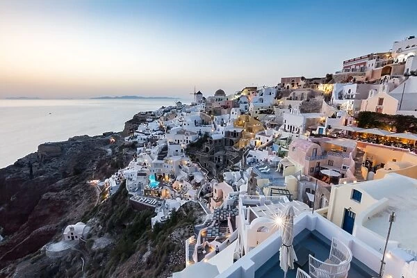 Sunset view over the whitewashed buildings and windmills of Oia, Santorini, Cyclades