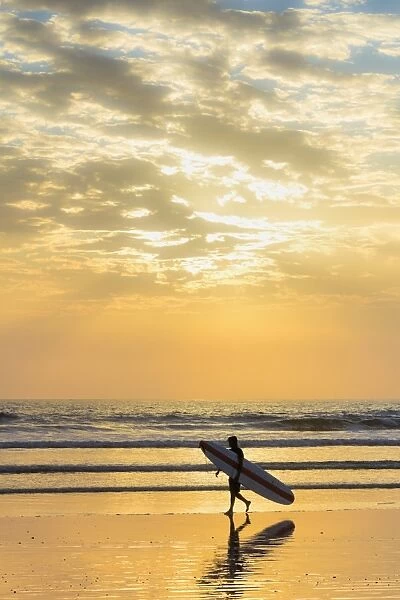 Surfer with long board at sunset on popular Playa Guiones surf beach, Nosara, Nicoya Peninsula, Guanacaste Province, Costa Rica, Central America