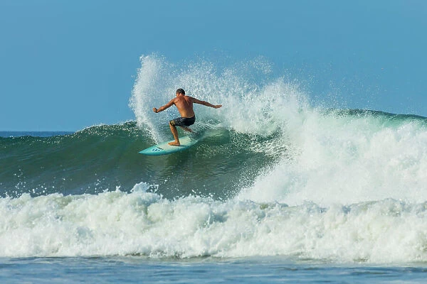 Surfer on shortboard riding wave at popular Playa Guiones surf beach, Nosara, Nicoya Peninsula, Guanacaste Province, Costa Rica, Central America