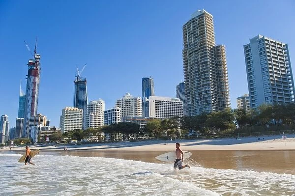 Surfers heading out to surf at Surfers Paradise beach, the Gold Coast, Queensland, Australia, Pacific