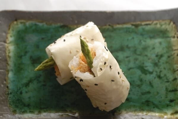 Sushi appetizer of salmon and asparagas in rice and sesame parcel