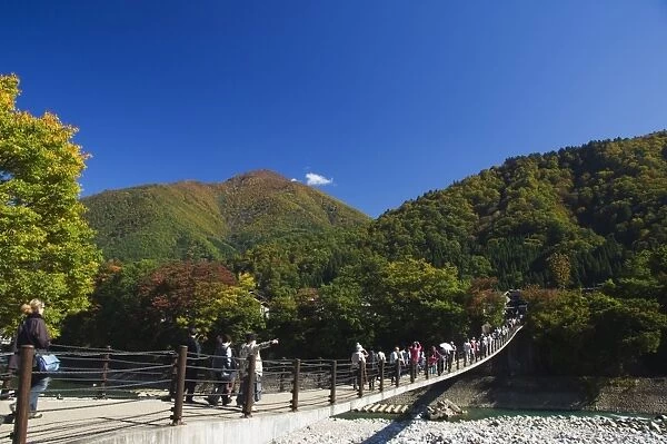 Suspension bridge with tourists looking at autumn colours