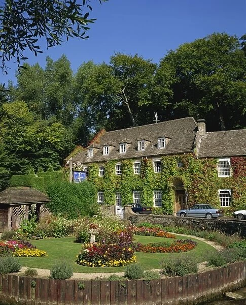 The Swan Hotel and garden full of summer flowers at Bibury, in the Cotswolds