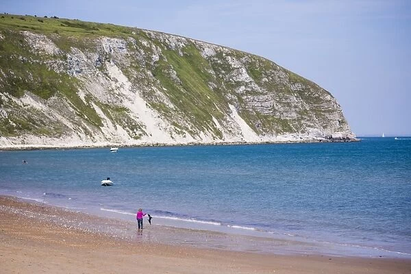 Swanage Beach, woman walking her dog under white cliffs, Dorset, Jurassic Coast, England, United Kingdom, Europe