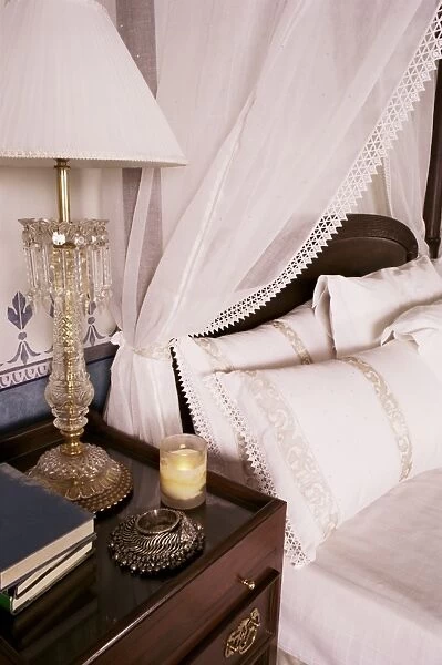 Detail of side table and four poster bed in bedroom