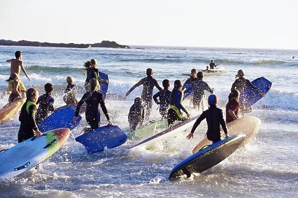 Teenage surfers running with their boards towards the