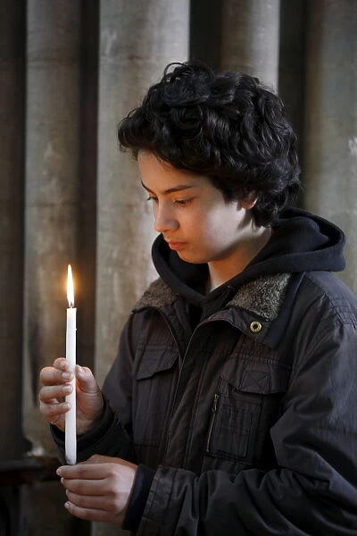 Teenager holding a candle in Notre Dame de Bayeux cathedral, Bayeux, Normandy, France