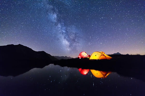 Tents reflected in the alpine lake on a starry night, Mont De La Saxe, Courmayeur