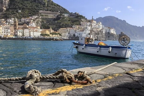 Tethered fishing boat with rope, Amalfi harbour, from quayside with view towards Amalfi town
