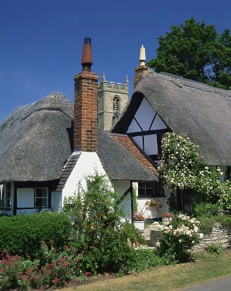 Thatched cottages, with the village church behind, at Welford on Avon in Warwickshire