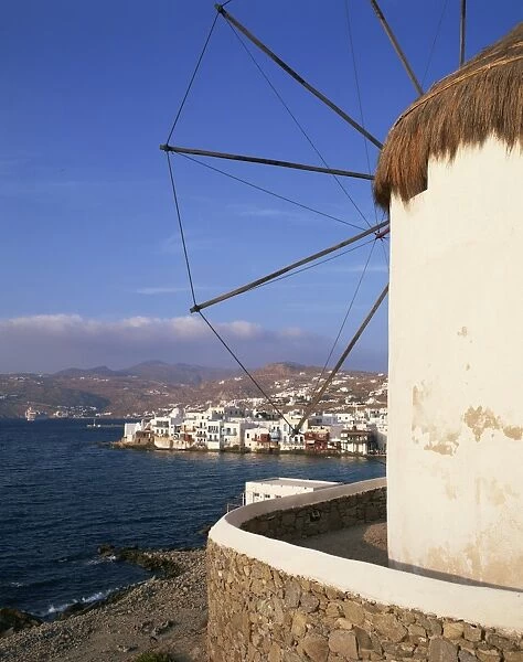 Thatched windmill with town and hills in the background on Mykonos