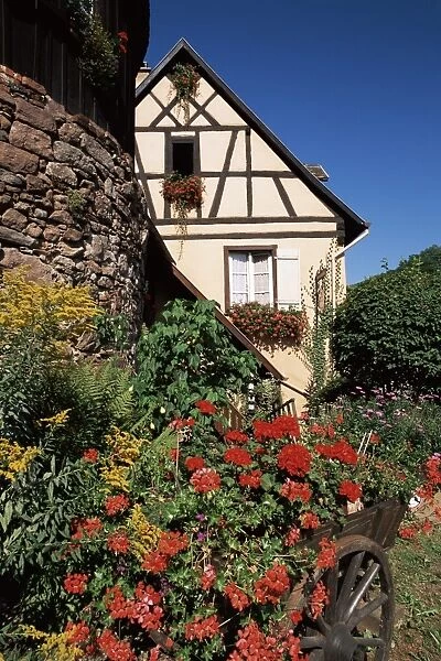 Timbered house and flower-filled cart, Riquewihr, Haut-Rhin, Alsace, France, Europe