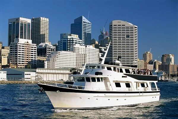 A tour boat in Darling Harbour, with the city skyline behind, in Sydney