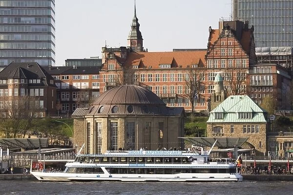 A tour boat docks by the St. Pauli Landing Stages (Landungsbruecken) while buildings of St