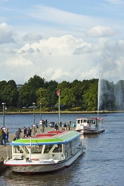 Tour boats that ply Alster Lake moored at the Jungfernstieg with the Lombardsbruecke beyond, Hamburg, Germany, Europe