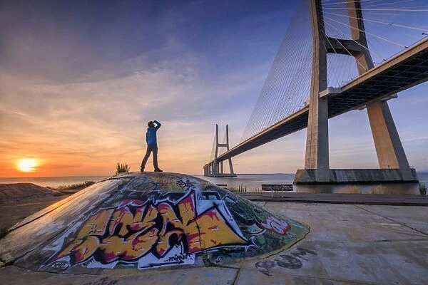 A tourist admires the majestic Vasco da Gama Bridge over the River Tagus, Parque das Nacoes