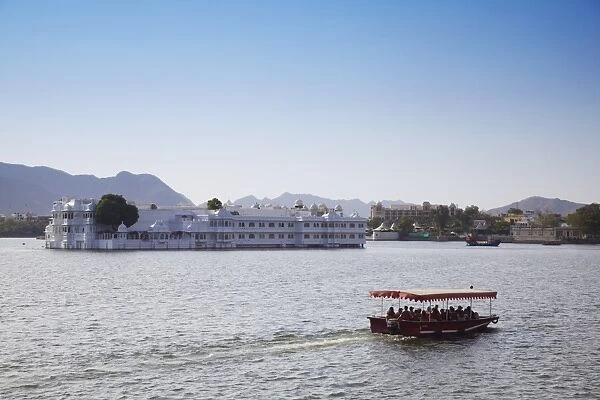 Tourist boat passing Lake Palace Hotel on Lake Pichola, Udaipur, Rajasthan, India, Asia