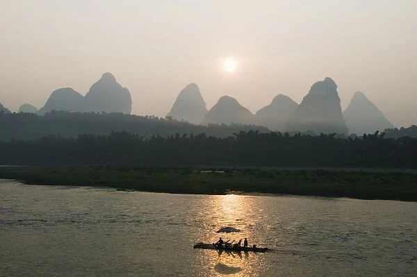 Tourist boat sailing through karst scenery at sunrise on the Li river