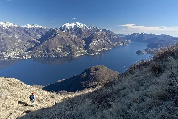 A tourist contemplating the landscape of Lake Como from a path in the High Route of Monti Lariani, with the village of Bellagio, Lombardy, Italy, Europe