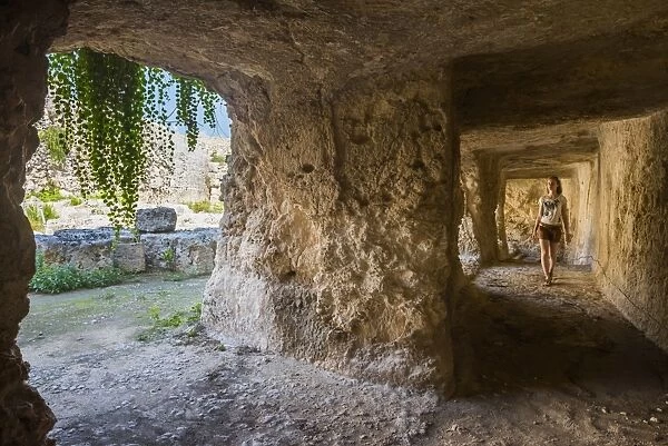 Tourist exploring the tunnels at the Greek ruins, Eurialo Casle (Castello Eurialo), Syracuse (Siracusa), Sicily, Italy, Europe