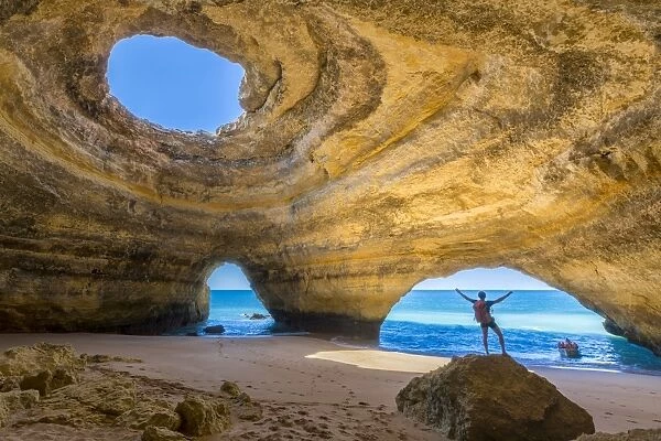 A tourist inside the sea caves of Benagil admires the clear waters of the Atlantic Ocean