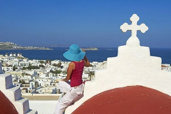Tourist on roof of red church above the old town, Mykonos town, Chora, Mykonos