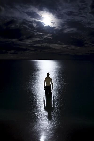 Tourist standing in the ocean watching the moon rise on Haad Rin Nai beach
