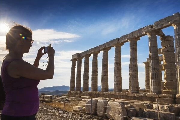 Tourist taking photo of Temple of Poseidon, Cape Sounion, near Athens, greece, Europe