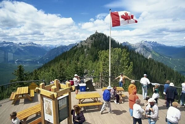 Tourists beneath the Canadian flag on Sulphur Mountain in the Banff National Park in Alberta