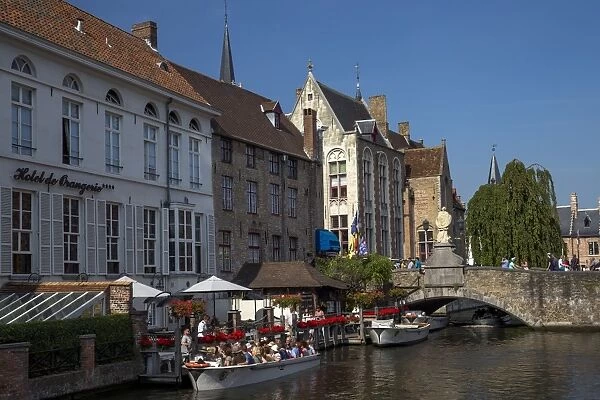 Tourists in boats travel on the Den Dijver canal in summer, Bruges, West Flanders