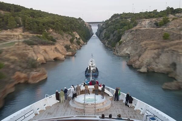 Tourists on the bow of a small cruise ship being pulled by a tug, early morning transit of Corinth Canal, Greece, Europe