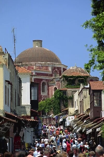 Tourists in busy back street with church dome behind