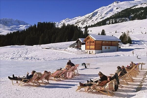 Tourists in deck chairs on the snow in winter at the