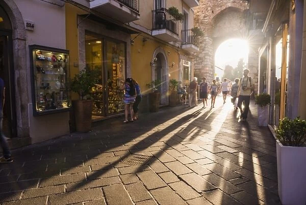 Tourists entering Corso Umberto, the main street in Taormina at sunset, Sicily, Italy, Europe
