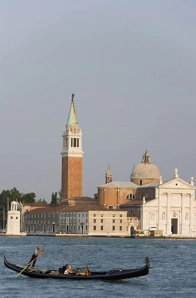 Tourists in gondola crossing the Bacino di San Marco in front of the tower of San Giorgio Maggiore