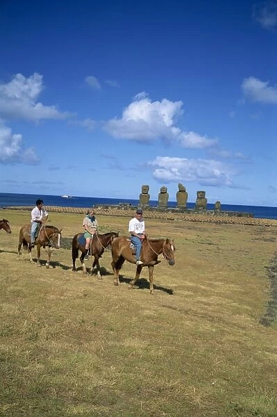 Tourists on horseback touring sites of moai or statues, at Ahu Vai Uri on Easter Island