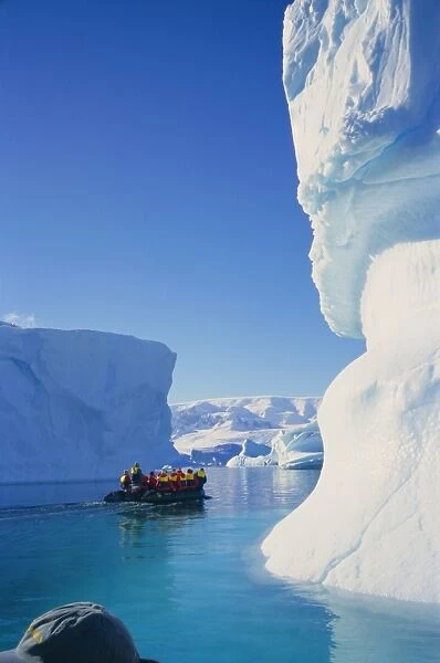Tourists in inflatable cruising past icebergs, Antarctica
