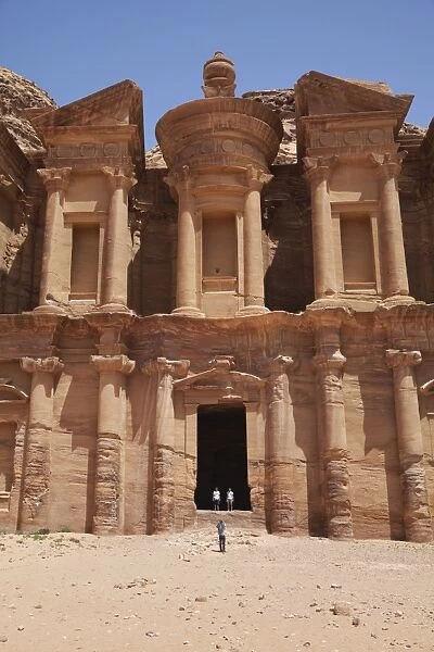 Tourists being photographed at the facade of the Monastery carved into the red rock at Petra, UNESCO World Heritage Site, Jordan, Middle East