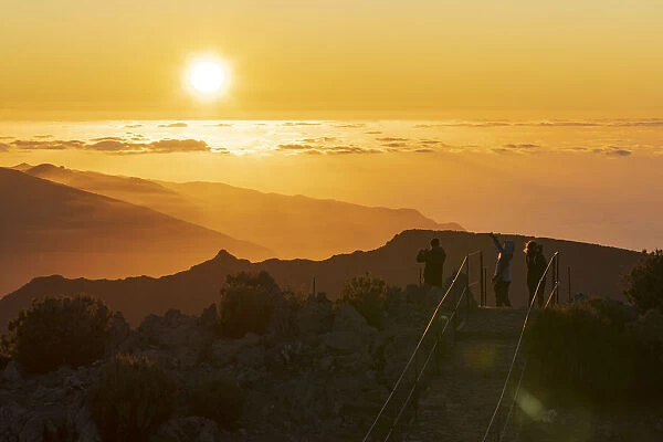 Tourists photographing sunset with smartphone from Pico Ruivo mountain peak, Madeira