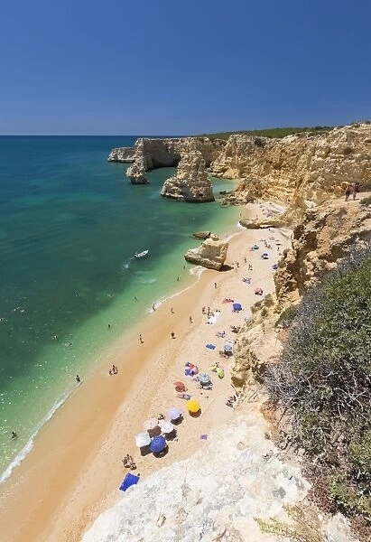 Tourists on sandy beach Praia da Marinha surrounded by turquoise ocean, Caramujeira