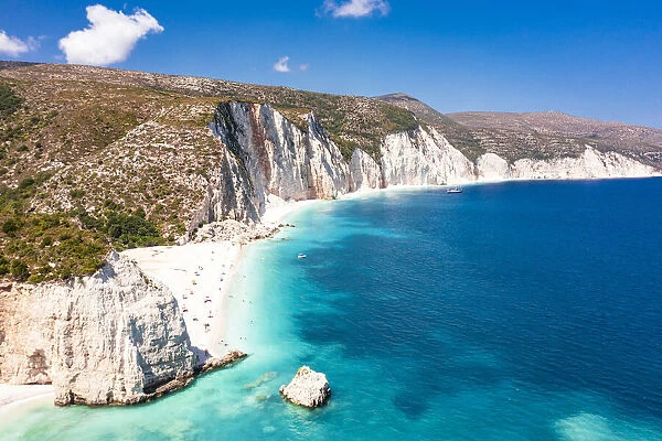 Tourists sunbathing at idyllic Fteri Beach set among cliffs and blue lagoon, overhead view, Kefalonia, Ionian Islands, Greek Islands, Greece, Europe