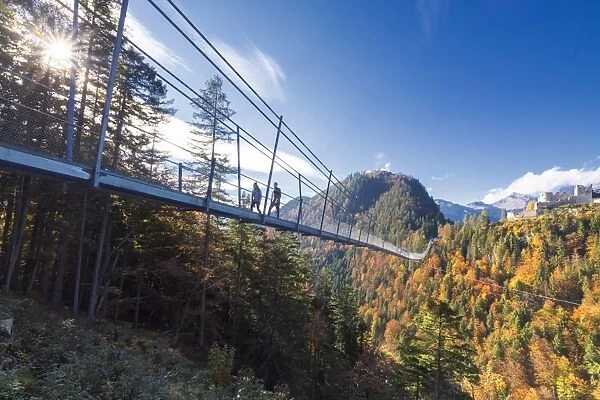 Tourists on the suspension bridge called Highline 179 framed by colorful woods in autumn