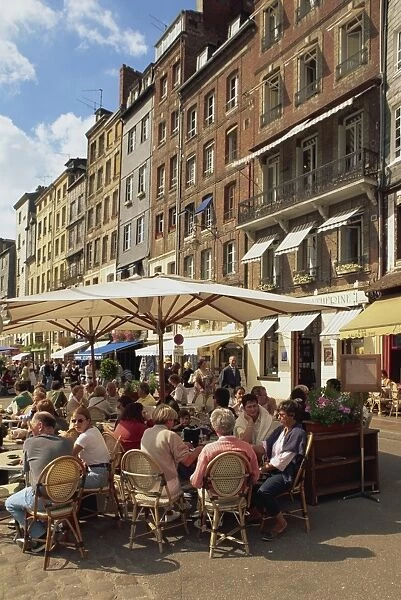 Tourists at tables in the waterfront pavement cafes and open air restaurants in the town of Honfleur, Basse Normandie (Normandy)
