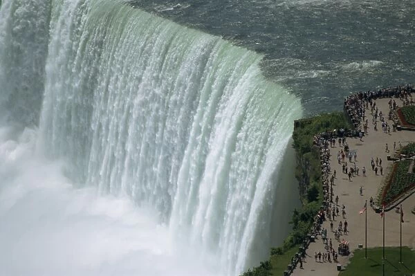Tourists on viewing platform on Canadian side of the waterfall view the Horseshoe Falls at Niagara