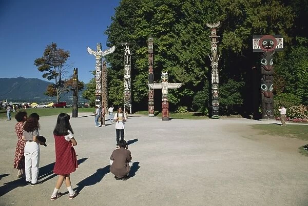 Tourists visiting Totems at Stanley Park in Vancouver, British Columbia